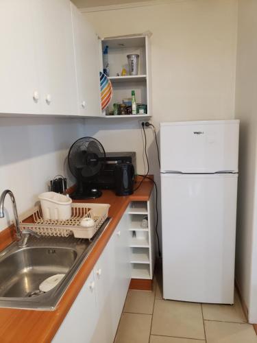 a kitchen with a sink and a white refrigerator at Departamento Tome in Tomé