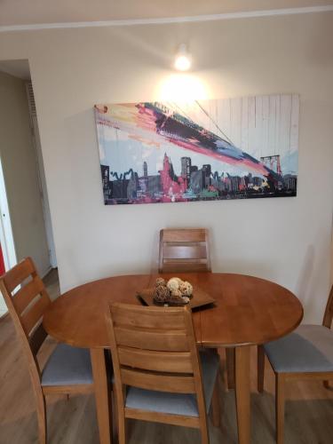 una mesa de comedor con sillas y una pintura en la pared en Departamento Tome, en Tomé