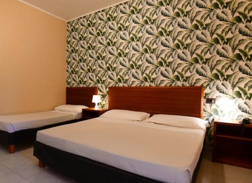 a bedroom with two beds and a wall mural at Hotel Riva Etrusca in Marina di Bibbona