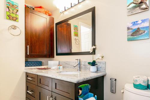 a bathroom with a sink and a mirror at Deluxe Living in Waikiki - Ocean View Condo with Parking in Honolulu