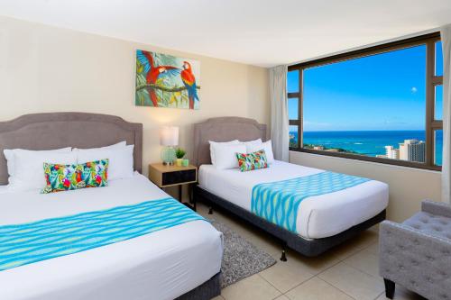 a bedroom with two beds and a large window at Deluxe Living in Waikiki - Ocean View Condo with Parking in Honolulu
