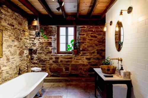 a bathroom with a bath tub and a stone wall at Randell's Mill - Adelaide Hills - Romantic Loft Stays in Gumeracha