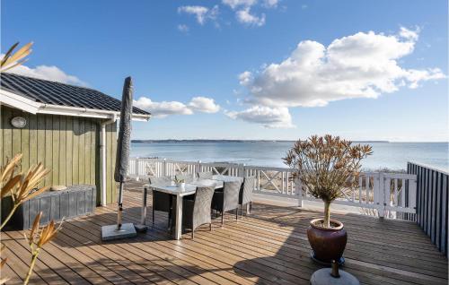 a deck with a table and chairs and the ocean at 2 Bedroom Gorgeous Home In Ebeltoft in Ebeltoft
