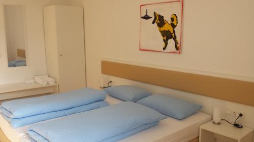 a bed with blue pillows and a picture of a dog at Manzoni Rooms in Merano