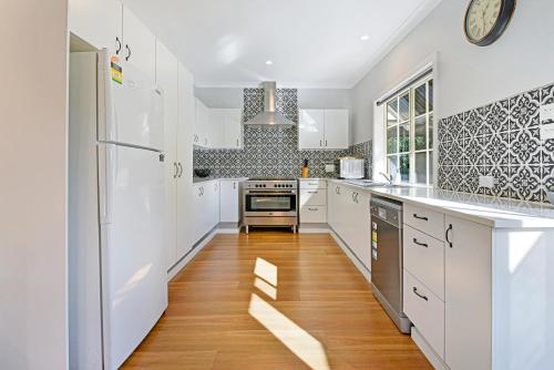 eine Küche mit weißen Schränken und Holzböden in der Unterkunft Cottage on Lords in Orange