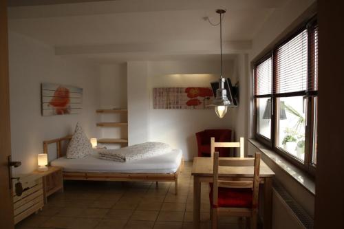 a bedroom with a bed and a table and a window at Hotel Anchovis in Mönchengladbach