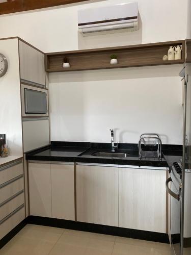 a kitchen with a sink and a microwave at Studio Recanto Beach Itapema in Itapema