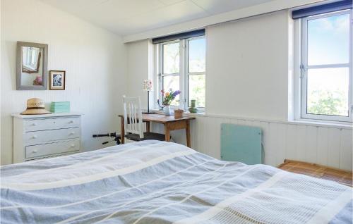 a bedroom with a bed and a desk and windows at Gorgeous Home In Svaneke With Wifi in Svaneke