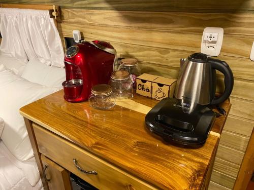 a coffee maker on a table next to a bed at Chale Sobre Rodas Spa Exclusive - Localizado Próximo do Centro in Canela