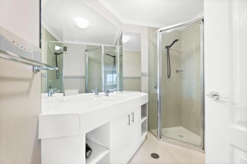 ein weißes Bad mit einem Waschbecken und einer Dusche in der Unterkunft Boardwalk unit 11 in Narooma