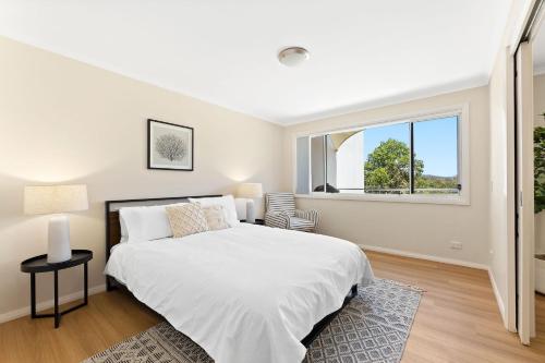 ein Schlafzimmer mit einem großen weißen Bett und einem Fenster in der Unterkunft Boardwalk unit 11 in Narooma