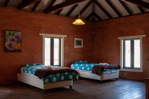 2 Betten in einem Zimmer mit 2 Fenstern in der Unterkunft 1885 Warehouse Apartment in Tumbarumba