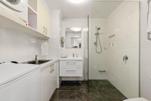 a white bathroom with a sink and a shower at Exclusive Stays - Rivergarden in Melbourne