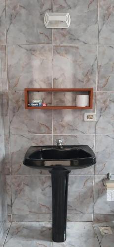 a bathroom with a black sink and a marble wall at Pousada Guarujá, suítes Praia do tombo in Guarujá