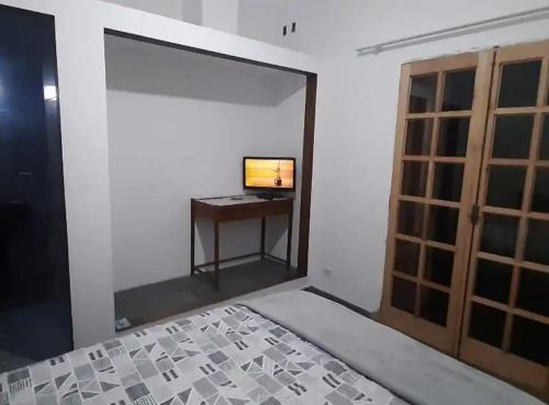 グアルジャにあるPousada Guarujá, suítes Praia do tomboのベッドとテレビ付きの机のある部屋