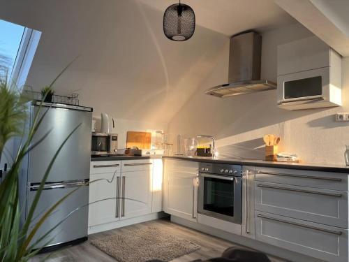 cocina con armarios blancos y nevera de acero inoxidable en 5Minuten von der City entfernte Wohnung mit Parkpl en Bielefeld