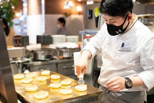 東京的住宿－DEL style Ikebukuro Higashiguchi by Daiwa Roynet Hotel，厨师在厨房里准备餐桌上的食品