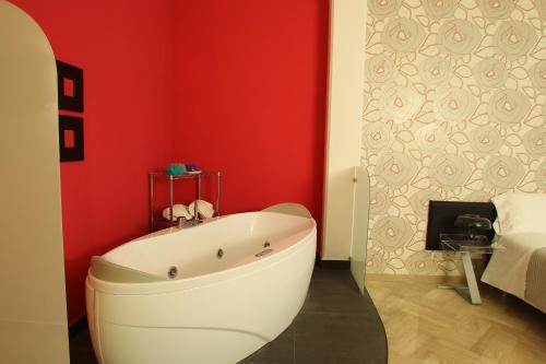 a bathroom with a white tub in a red wall at Viasparano B&B in Bari