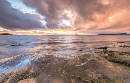 a sunset over the ocean with rocks in the water at Holiday Home Vallersund Nausthylla Haldorhamn in Drilen