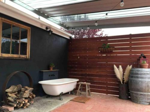 y baño con bañera junto a una pared de madera. en Randell Cottage - Adelaide Hills - Cosy Rustic Hideaway, en Gumeracha