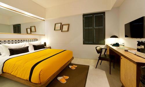 a bedroom with a yellow bed and a desk with a computer at Kosenda Hotel in Jakarta