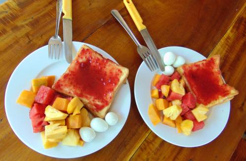 Twee witte borden met eten en fruit op een tafel. bij Brown House Resort in Can Tho