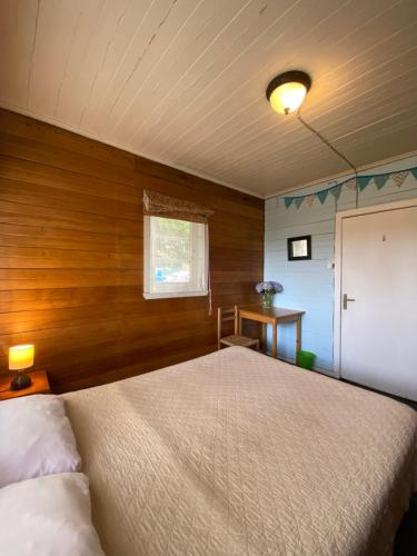 1 dormitorio con 1 cama y pared de madera en La Guapa Hostel, en Puerto Varas