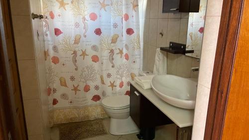 a bathroom with a toilet and a sink and a shower curtain at Lagun Ocean View Villa with Own Private Beach in Willemstad