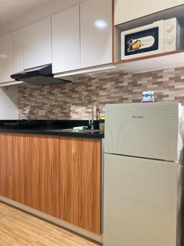 a kitchen with a white refrigerator and wooden cabinets at 1523 MIGAs Haven at Sunvida across SM City in Cebu City