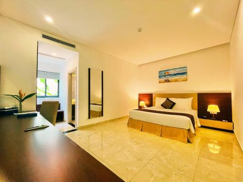 Diamond Bay Condotel Resort Nha Trang في نها ترانغ: غرفة نوم بسرير ومكتب فيه مصباحين
