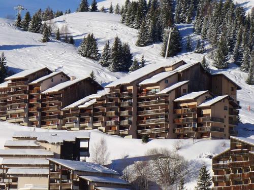 un complexe dans la neige avec des bâtiments recouverts de neige dans l'établissement Studio cabine au pied des pistes, 3 couchages, parking - FR-1-297-326, à Auris