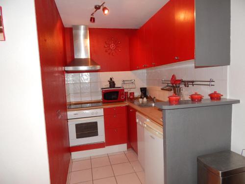 - une cuisine rouge avec des placards rouges et un four micro-ondes dans l'établissement Villa à 50 m de la plage du Grazel pour 6 personnes, à Gruissan