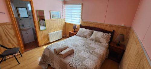 1 dormitorio con 1 cama grande y baño en Casa Hospedaje Costanera, en Puerto Natales