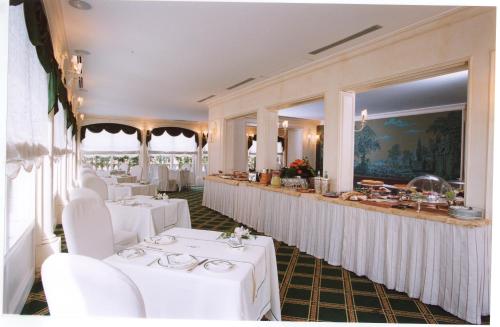 カターニアにあるホテル ヴィラ デル ボスコの白いテーブルと白い椅子が備わるレストラン
