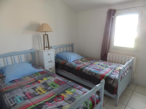 une chambre avec deux lits jumeaux et une fenêtre dans l'établissement Villa à 50 m de la plage du Grazel pour 6 personnes, à Gruissan