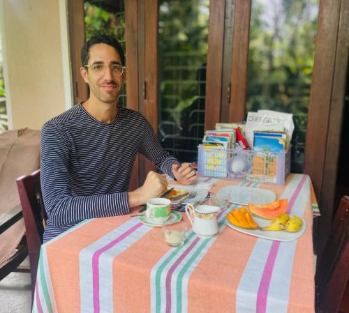 Green Grass Homestay في سيجيريا: رجل يجلس على طاولة مع طبق من الطعام