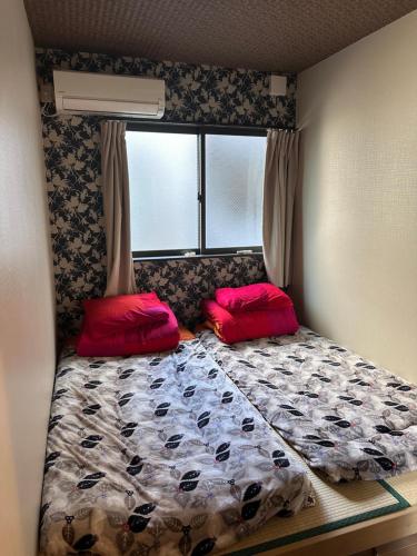 大阪市にある智TOMOの小さなベッドルーム(赤い枕2つ付きのベッド1台付)