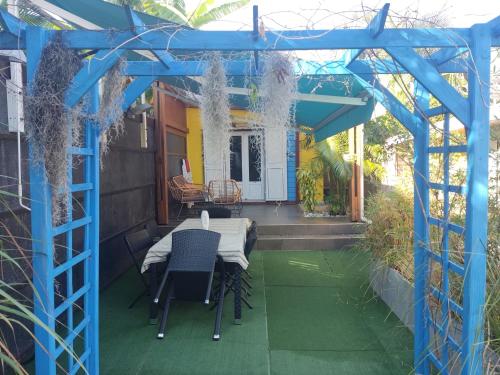 a blue pergola on a house with a table and chairs at La Plainitude in Le Bois de Nèfles