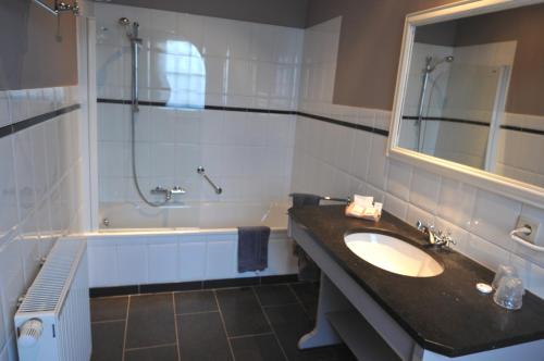 een badkamer met een wastafel, een douche en een bad bij Hostellerie au Coeur du Spinois in Rebecq-Rognon