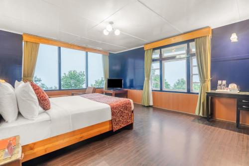 a bedroom with a bed and a desk and windows at Summit Tashi Ghang Heritage Resort in Pelling