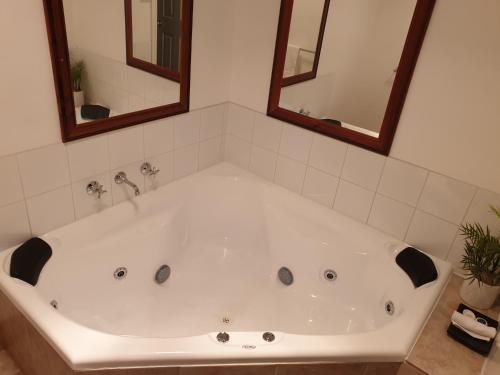 uma banheira branca numa casa de banho com 2 espelhos em Chateau Bass em Bass