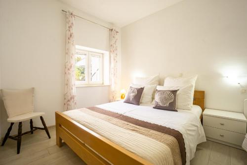 a bedroom with a bed with a chair and a window at Babara beautiful setting right on beach with modern facilities in Metajna