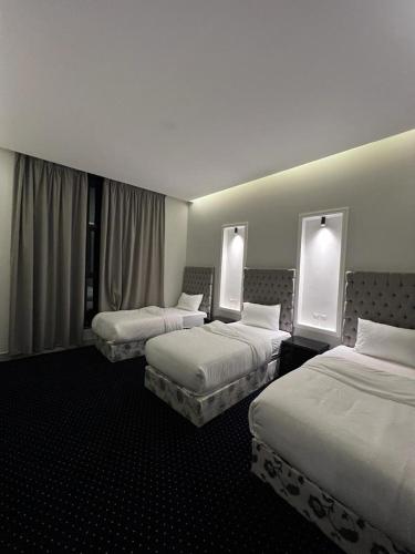 een hotelkamer met 3 bedden en 2 ramen bij شاليه كريكت in Abha