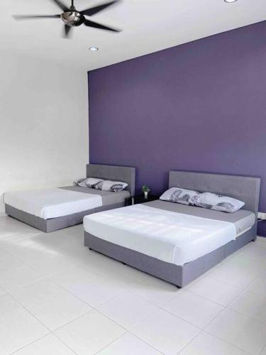 2 Betten in einem Schlafzimmer mit einer lila Wand in der Unterkunft Niana Homestay Melaka -near town in Malakka