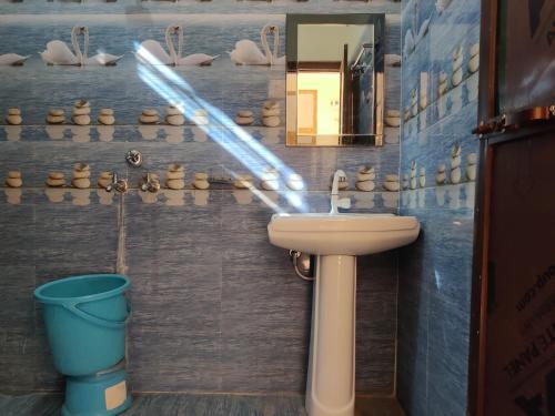 a bathroom with a sink and a mirror and a bucket at Corbett Rejoice Home Stay in Jhirna