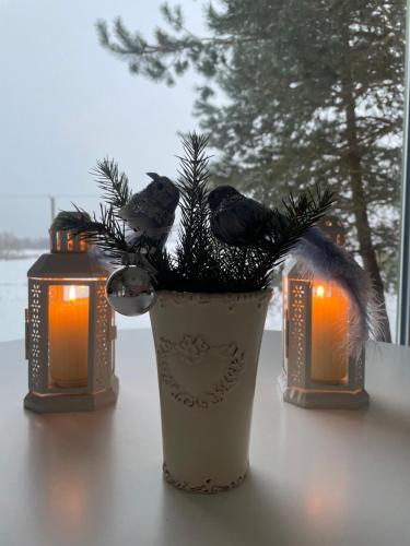 a vase with christmas trees and candles on a table at ALANTOS ŽIRGAI Holiday Villas sauna or hottube additional price in Alanta