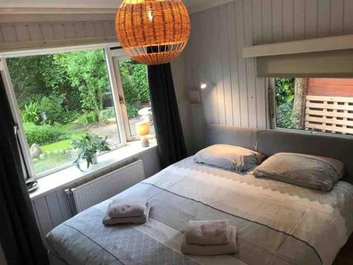 a bedroom with a bed and a large window at Private Big Garden double Chalet with Outside HOTTUB and BARRELSAUNA, Woodside, Nature in Voorthuizen