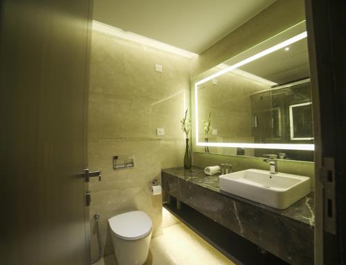 a bathroom with a sink and a toilet and a mirror at BNGV Mystic Premier Hotel in Bangalore