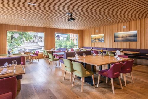 un restaurante con paredes de madera, mesas y sillas en Hotel Gasthof Adler, en Lingenau