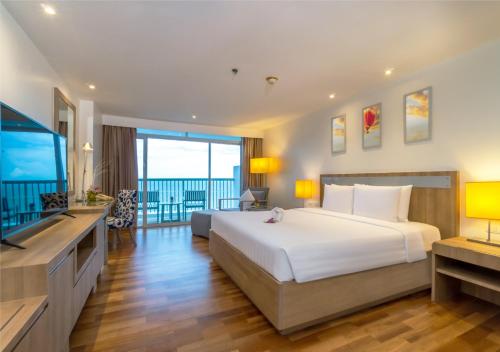 a bedroom with a large bed and a flat screen tv at Radisson Resort & Spa Hua Hin in Cha Am